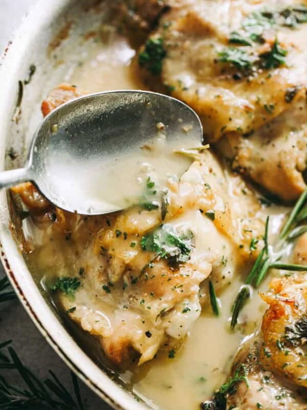 spooning garlic sauce over pan seared chicken thighs.