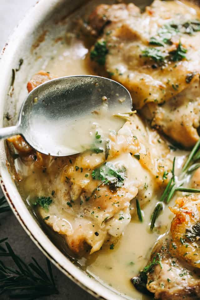 spooning garlic sauce over pan-seared chicken thighs.