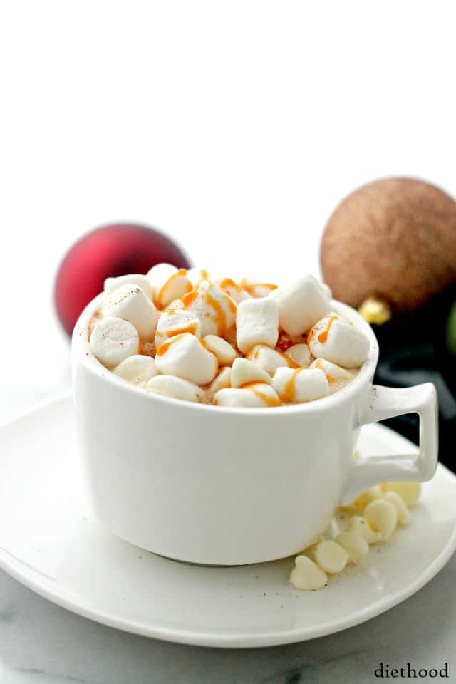 Close-up view of Vanilla Latte White Hot Chocolate in a mug topped with marshmallows, white chocolate chips, and caramel drizzle