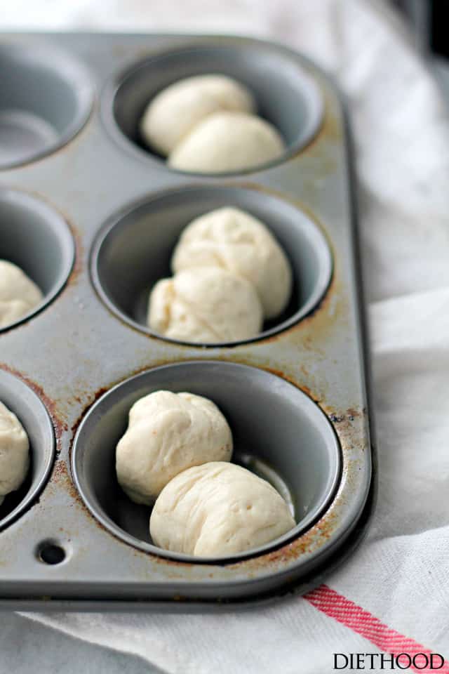 Pairs of dough balls set in muffin tin cups, ready to be baked