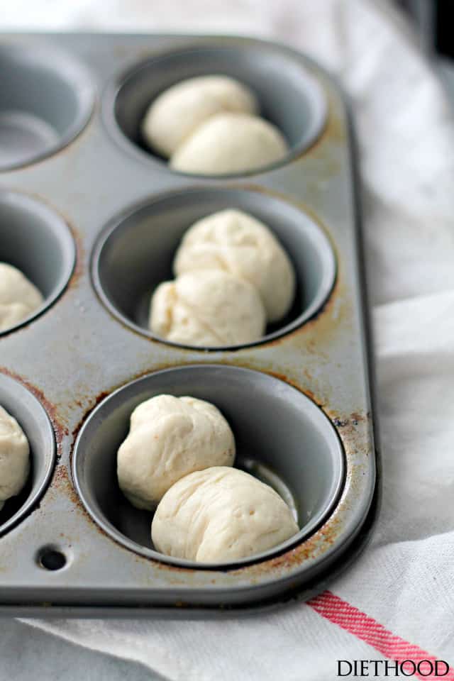 Pairs of dough balls set in muffin tin cups, ready to be baked.