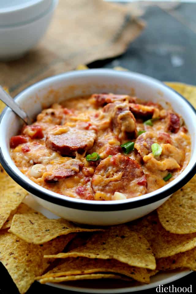 Bowl of sausage cheese dip with green onions on top.