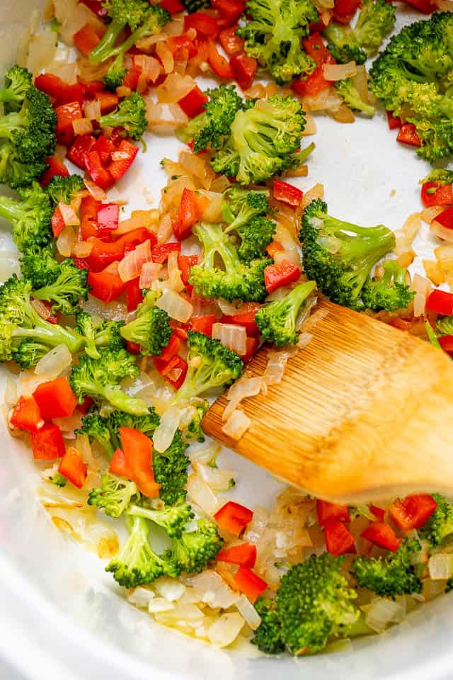 mixing together broccoli florets, onions, and red peppers