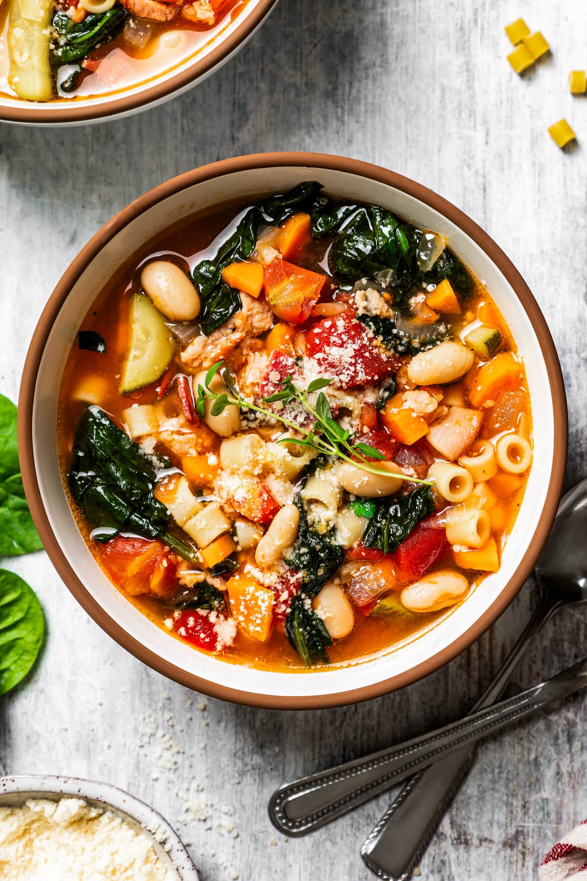 Close up of a bowl of minestrone soup topped with grated parmesan cheese.