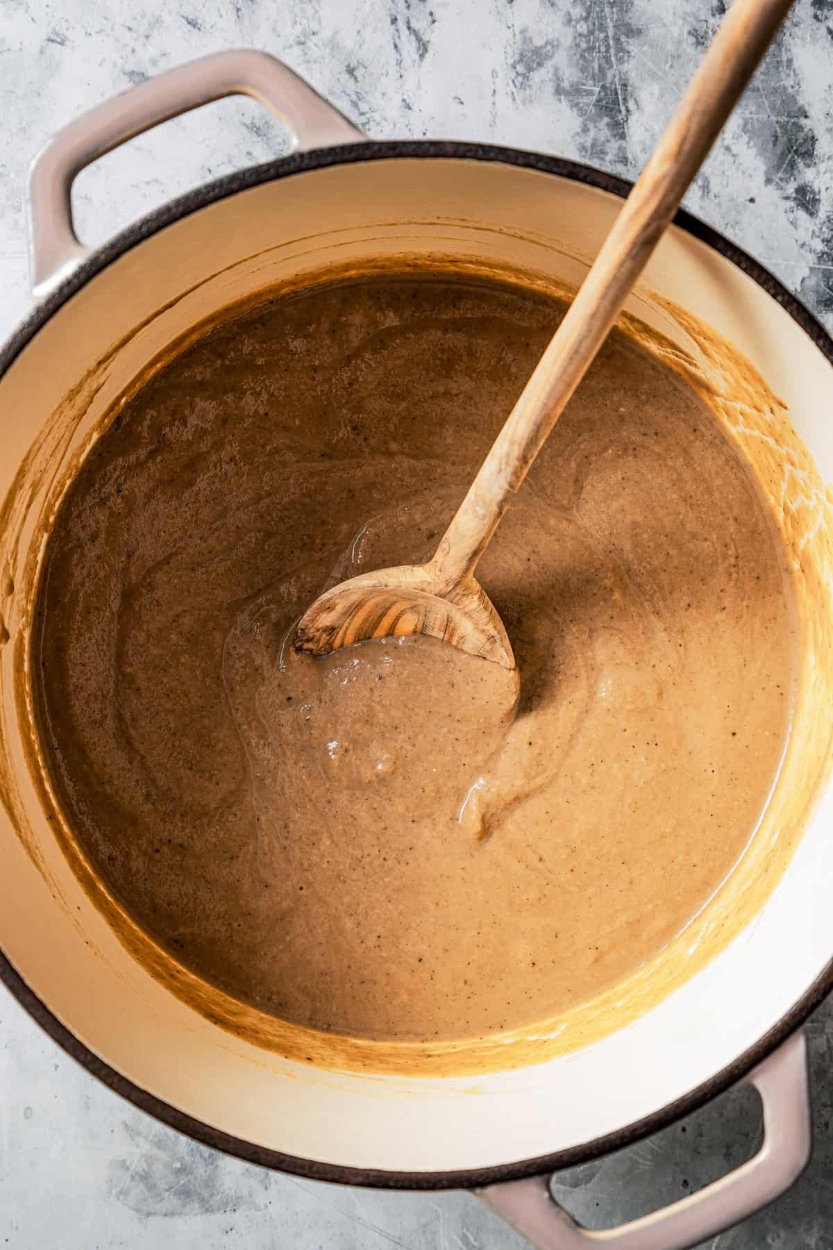 Mushroom soup in a large pot with a wooden spoon.