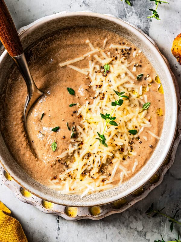 Creamy mushroom soup served in a bowl with a garnish of shredded parmesan and fresh herbs.