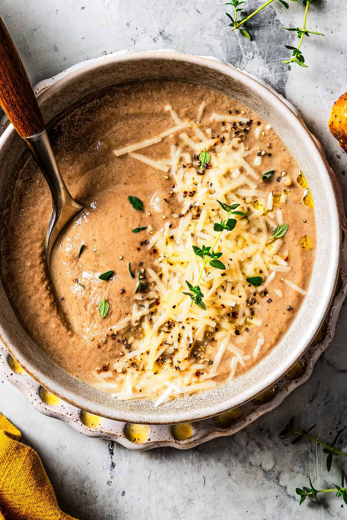 Creamy mushroom soup served in a bowl with a garnish of shredded parmesan and fresh herbs.