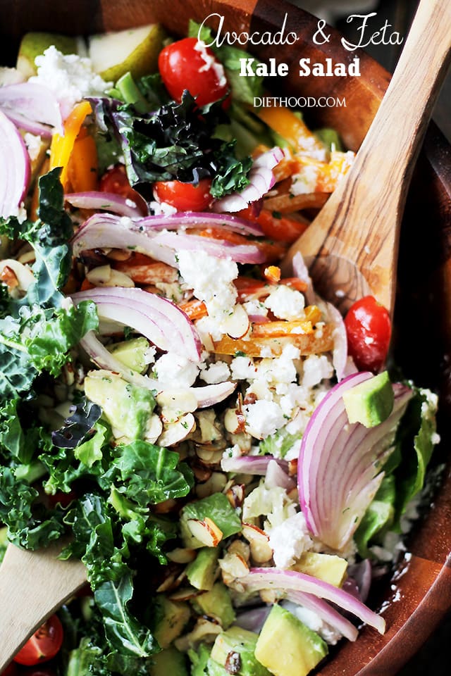 A bowl filled with kale, avocado, pears, almonds, raisins, tomatoes, peppers and Garlic Dijon Vinaigrette