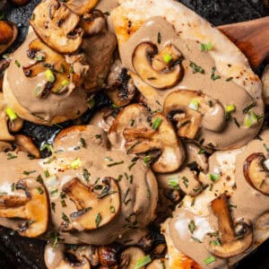 Close up of chicken dijon covered with mushroom sauce in a cast iron skillet.