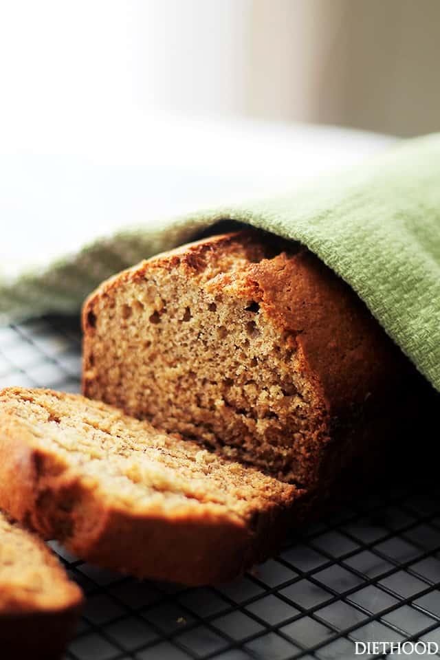 Sliced banana bread partially covered with a green kitchen towel.