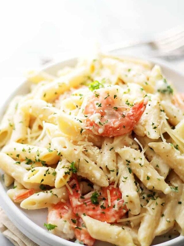 Lemon shrimp pasta in a white bowl topped with parmesan cheese and fresh minced parsley.