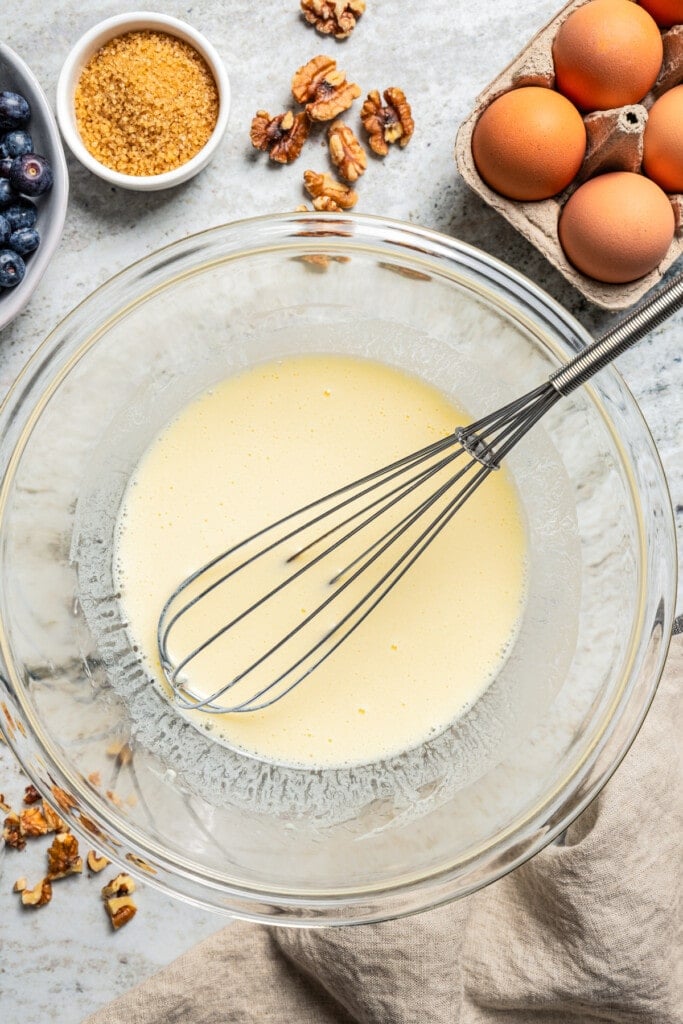 A whisk in a bowl, whisking eggs.
