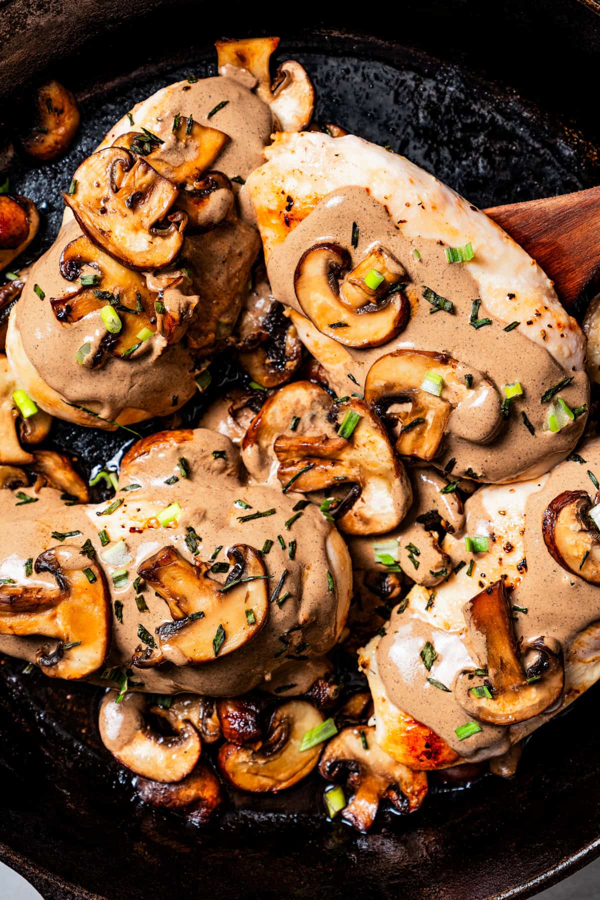 Close up of chicken dijon covered with mushroom sauce in a cast iron skillet.