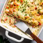 Overhead image of serving chicken enchilada casserole with a metal spatula.