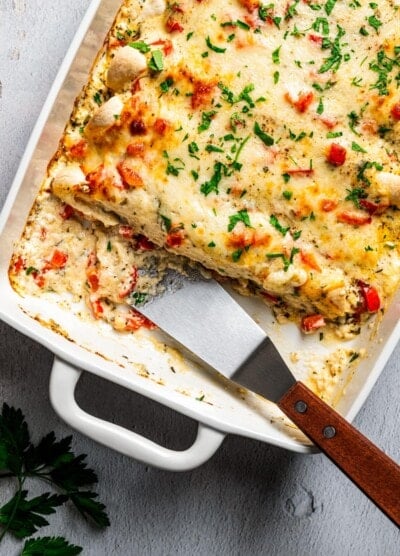 Overhead image of serving chicken enchilada casserole with a metal spatula.