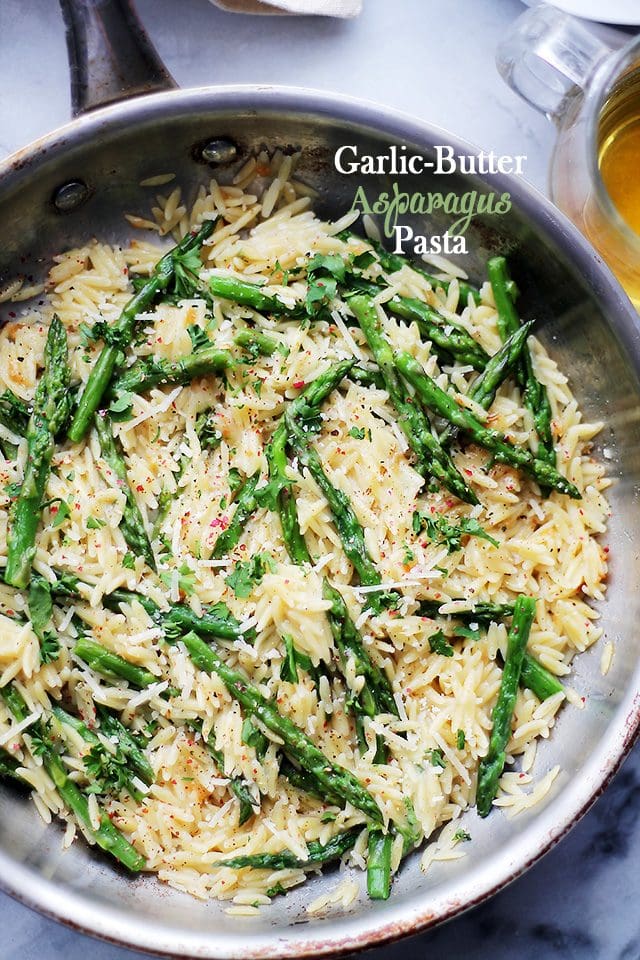 Orzo pasta and asparagus in a skillet with parmesan cheese.