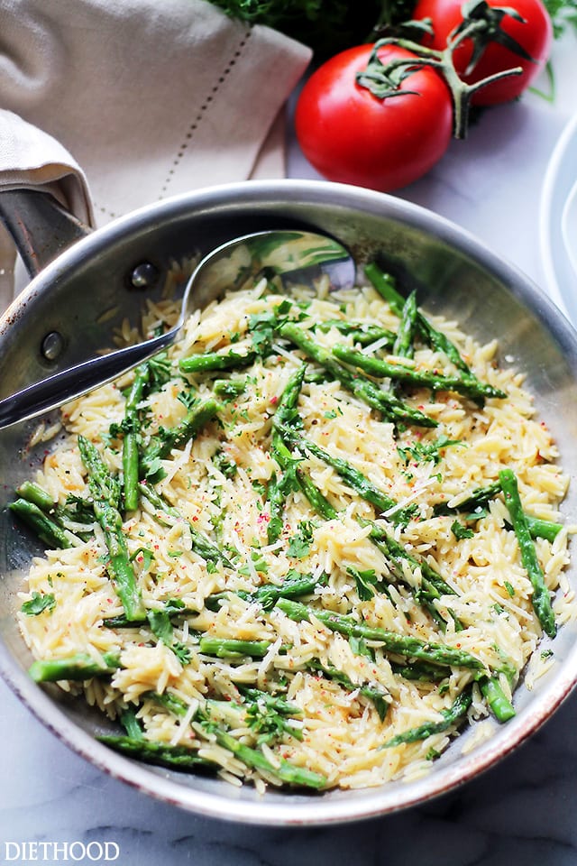 Asparagus pasta in a pan with parmesan cheese and garlic butter sauce.