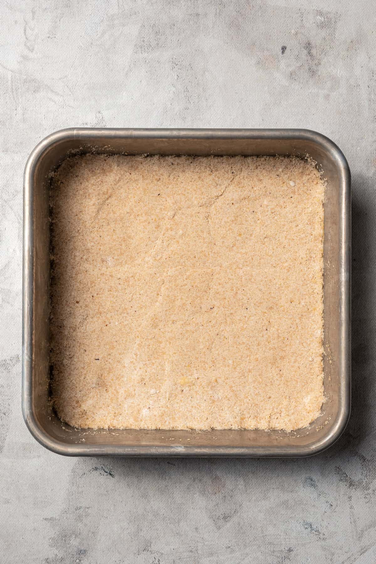 Cookie crust pressed into the bottom of a square baking pan.