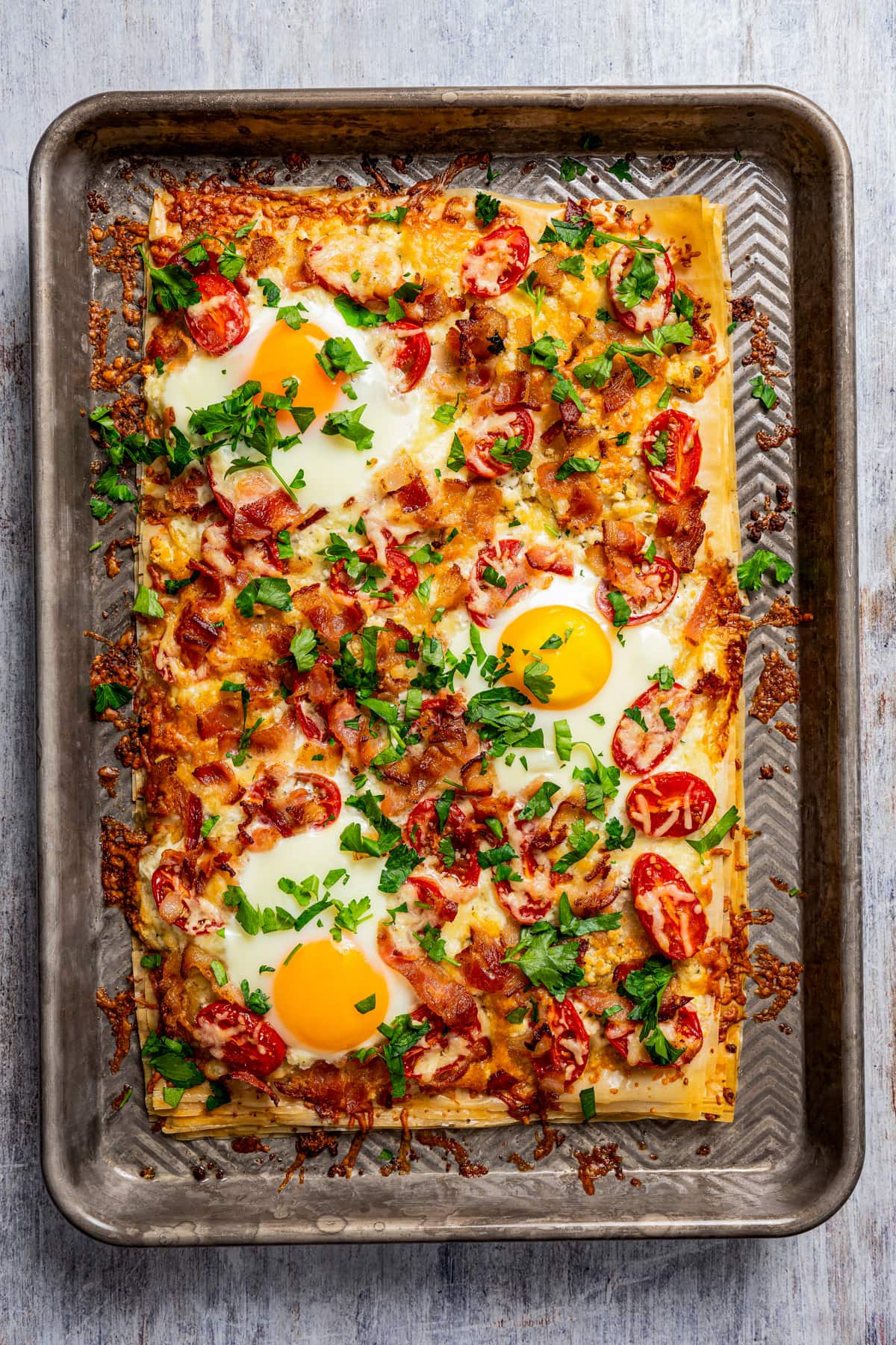 Stacked and baked Phyllo sheets topped with eggs, bacon, and tomatoes.