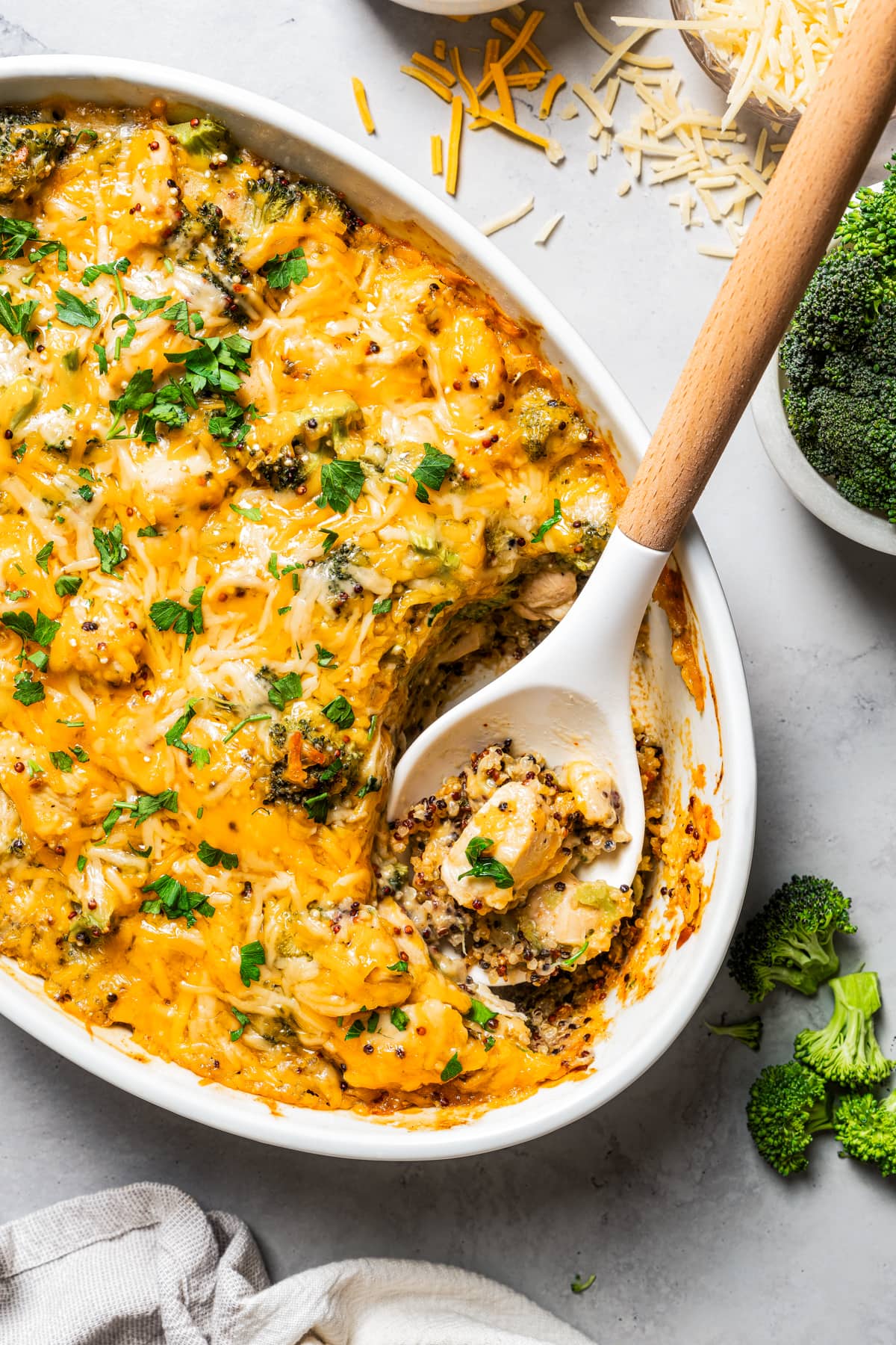 A serving spoon scooping out Chicken and broccoli from a casserole dish.