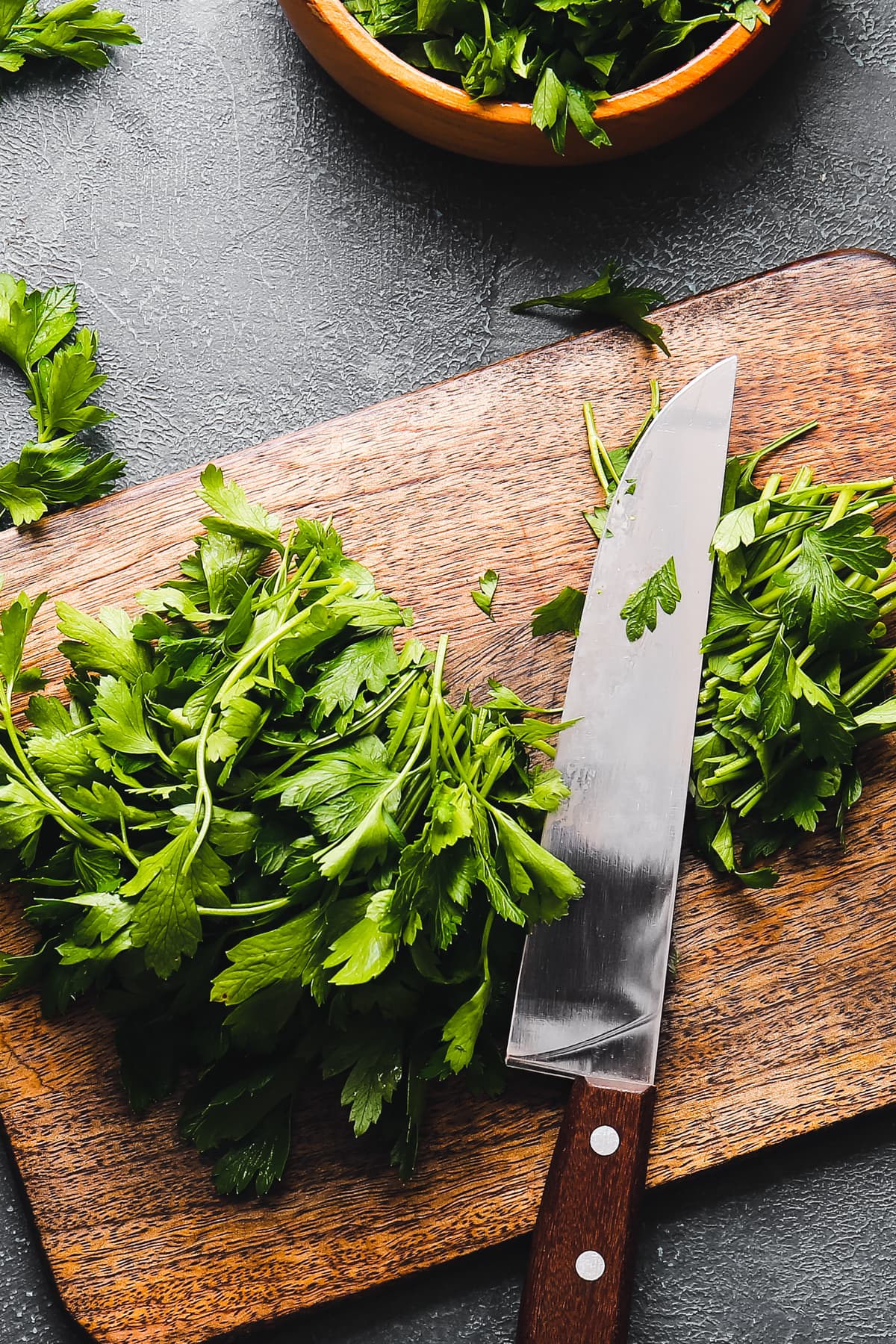 Chopping parsley on a wooden board.