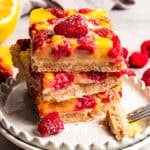 A stack of raspberry lemon bars on a plate by diethood.com