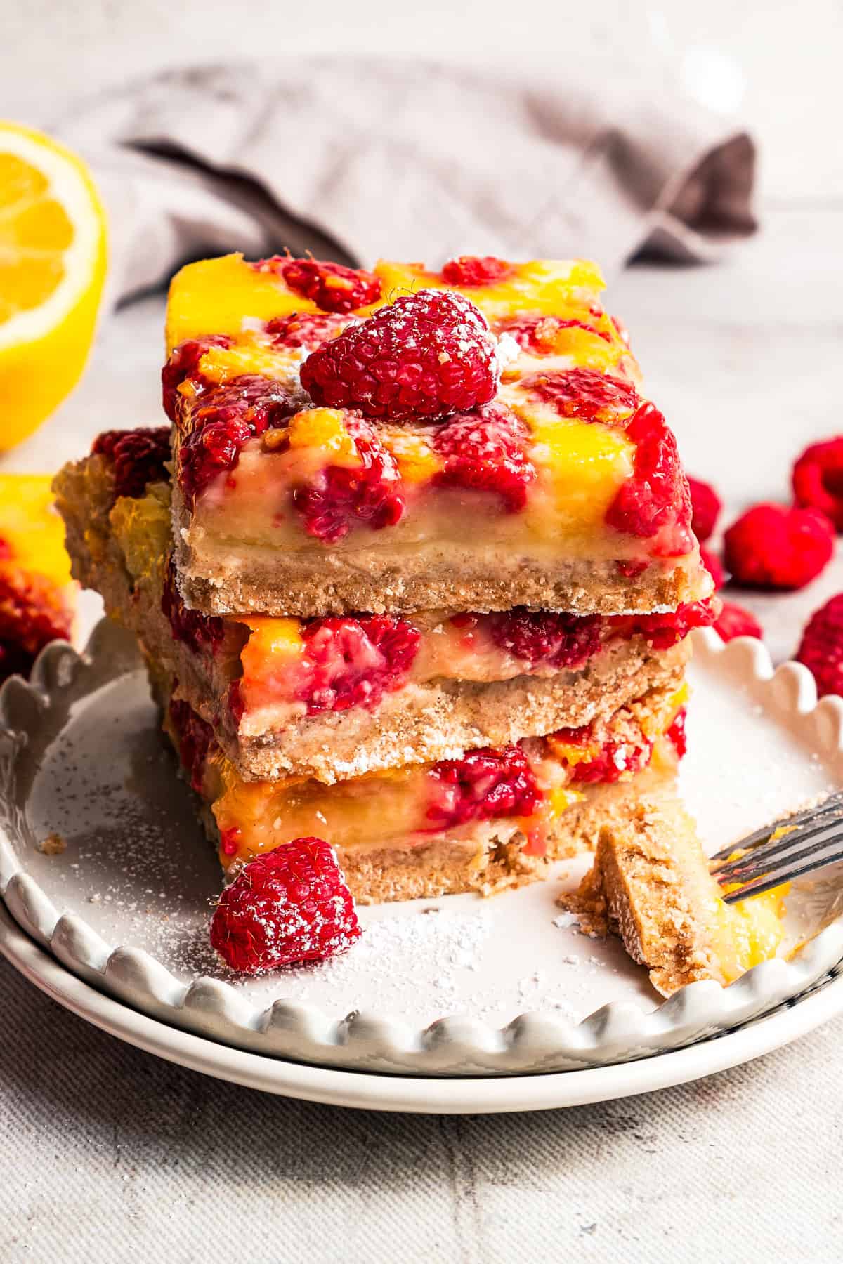 A stack of raspberry lemon bars on a plate by diethood.com