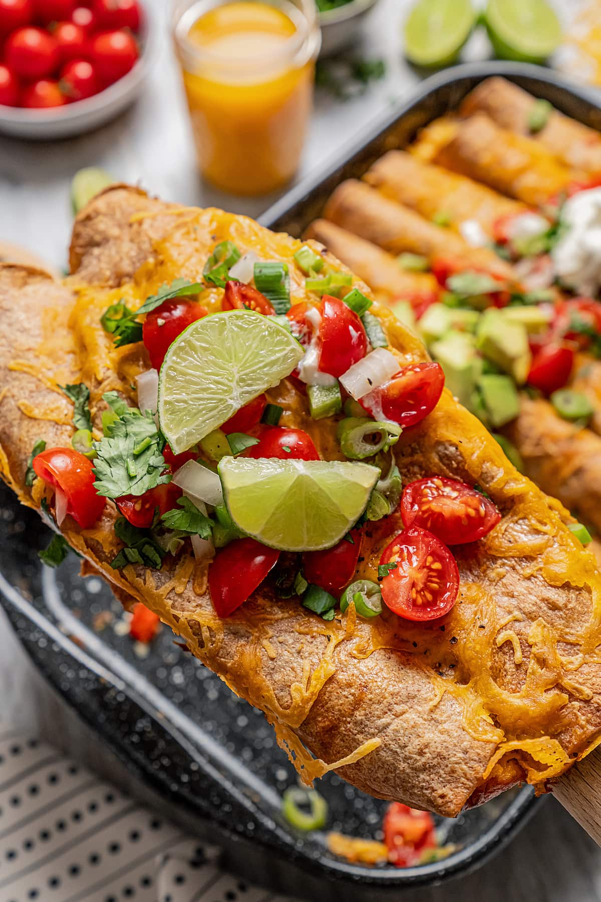 Fill soft tortillas with sausage, peppers, and cheese, and wake up to these ready-to-bake breakfast enchiladas for an easy Tex-Mex brunch! Close-up of enchiladas with toppings.