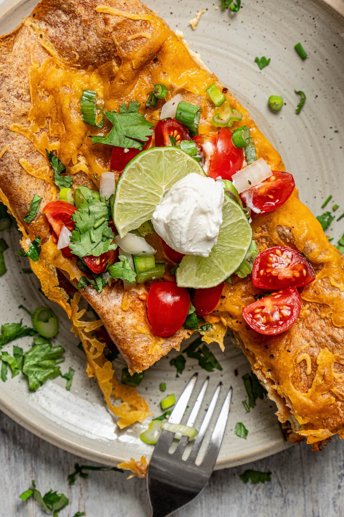 Breakfast enchiladas on a plate with toppings. 