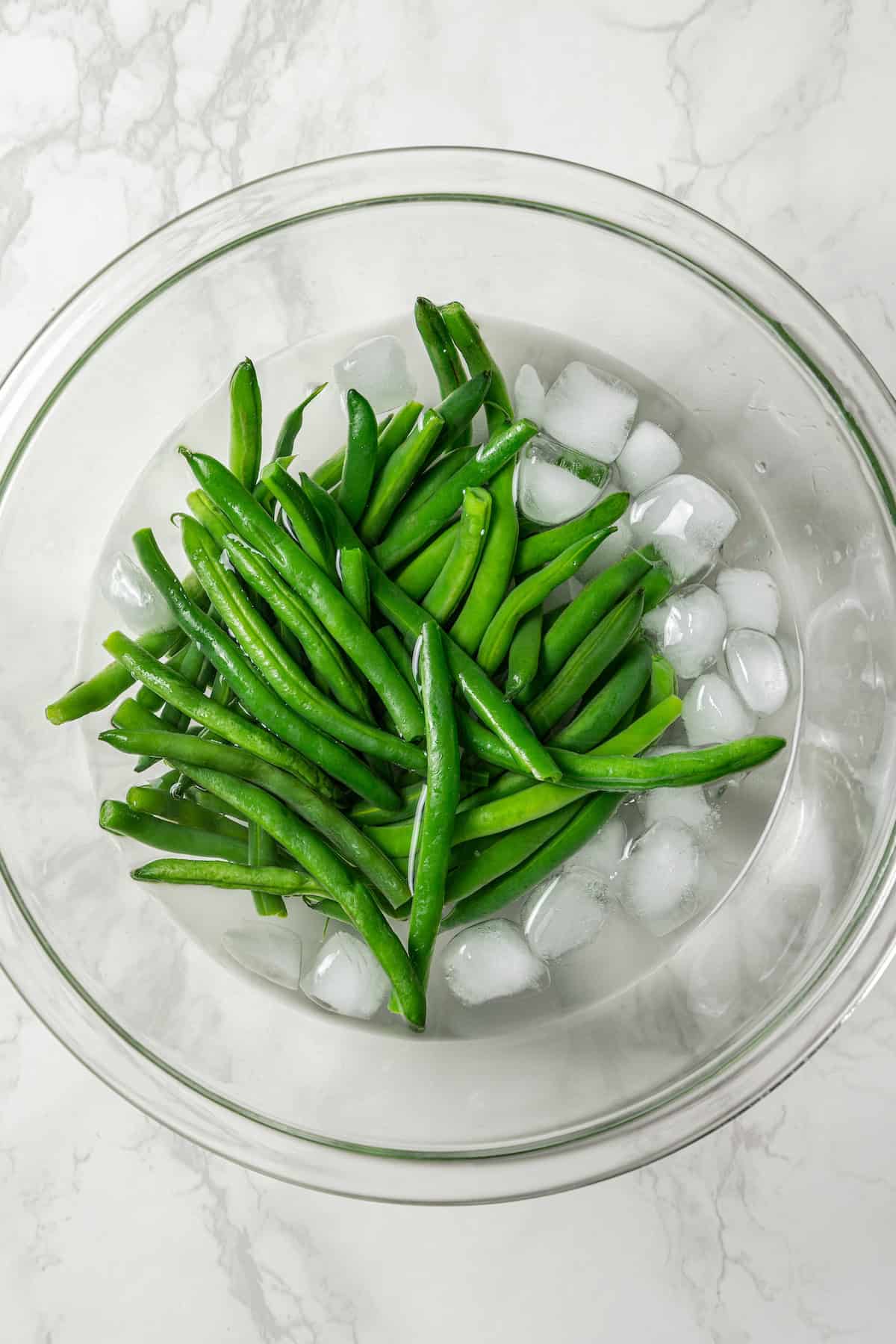 Blanched green beans in a bowl of ice water.