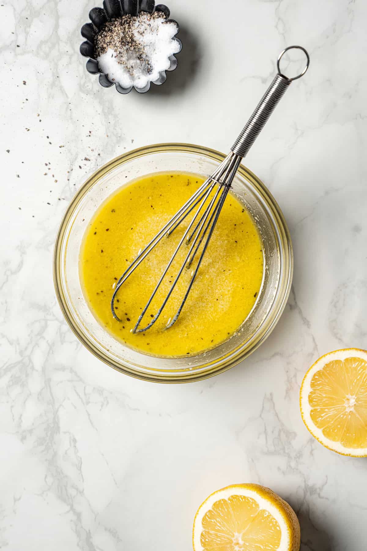 Vinaigrette ingredients combined in a bowl with a whisk.