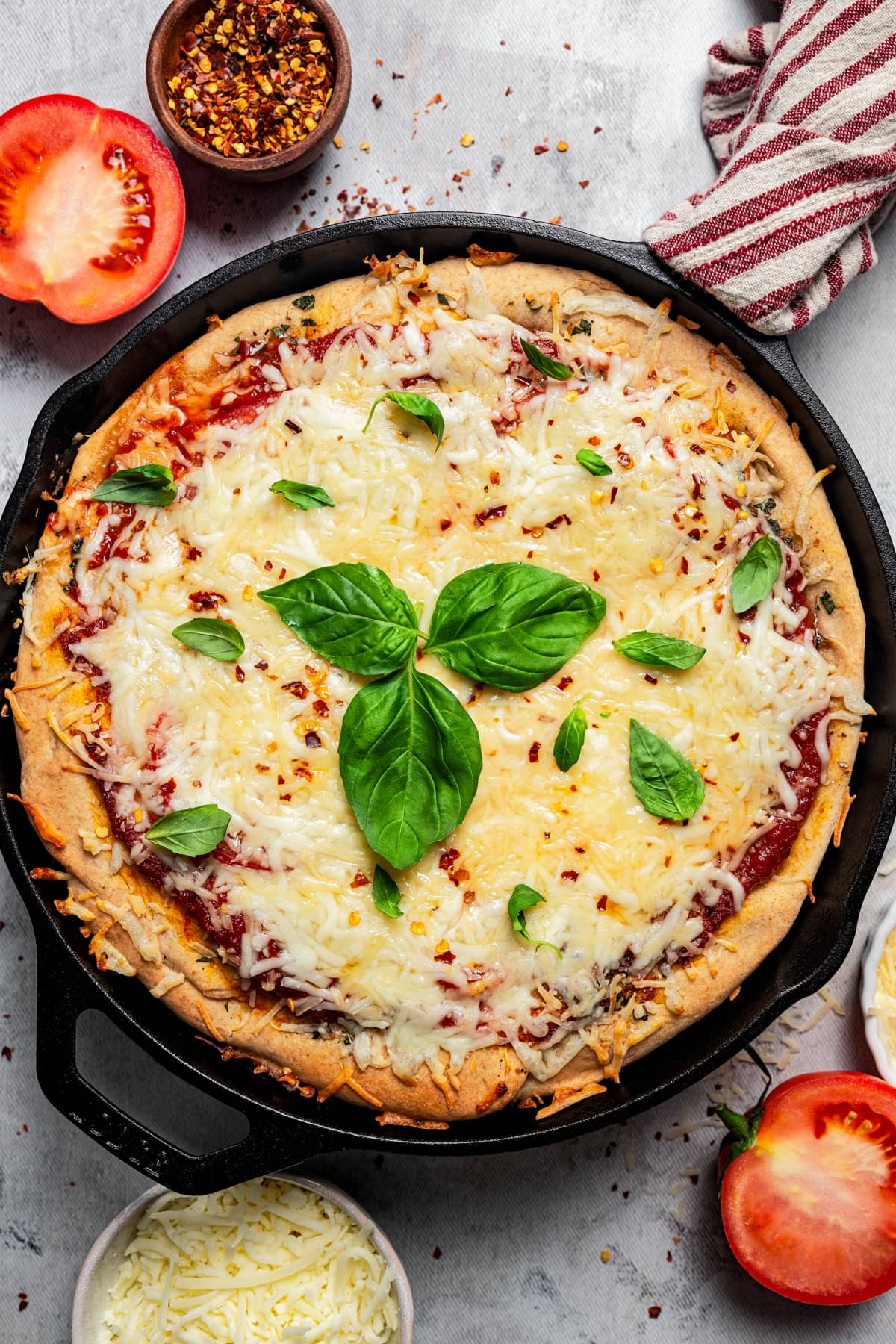 Whole pizza in a skillet topped with fresh basil.