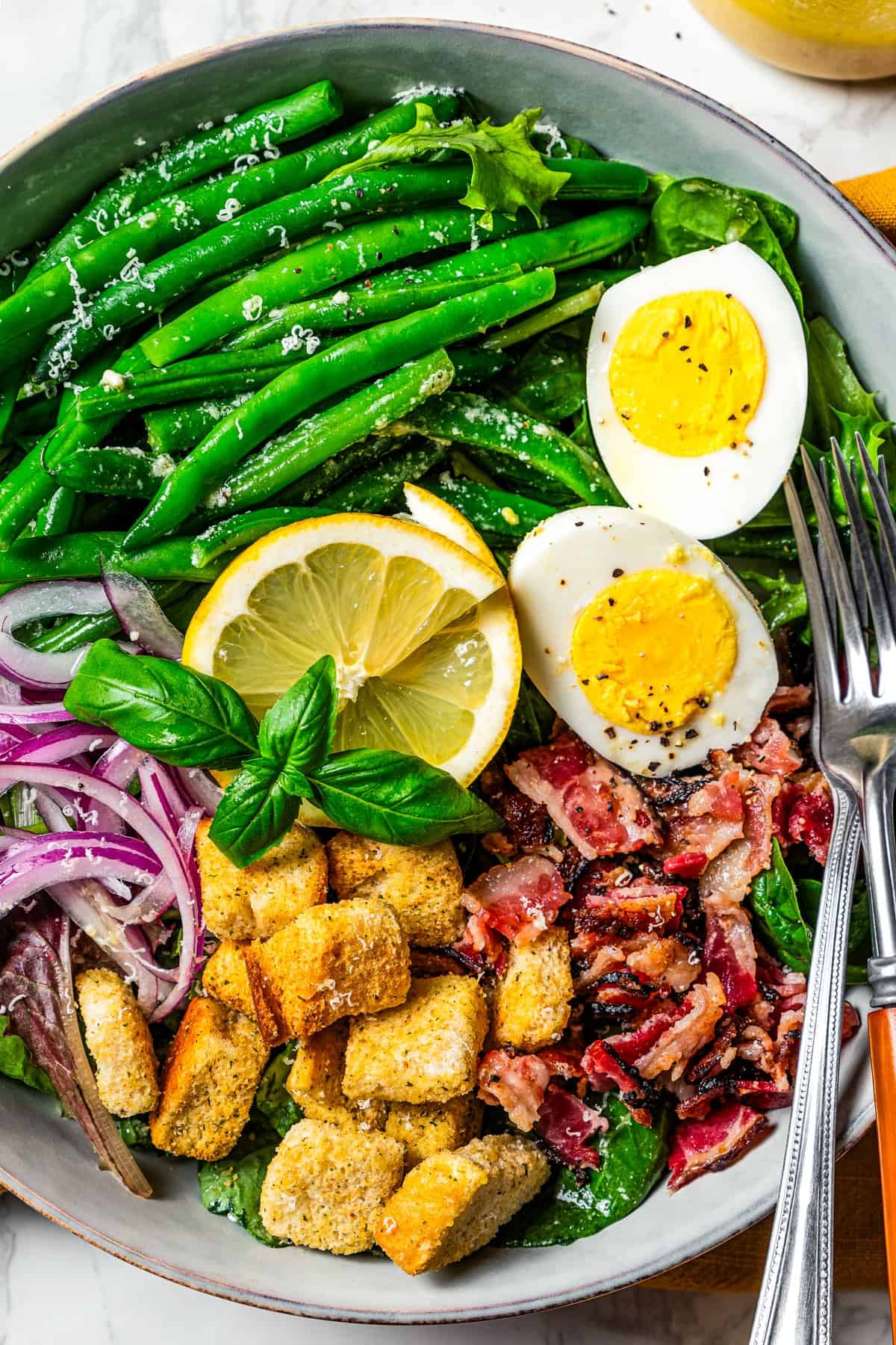 Green bean salad served in a bowl with a fork and knife.