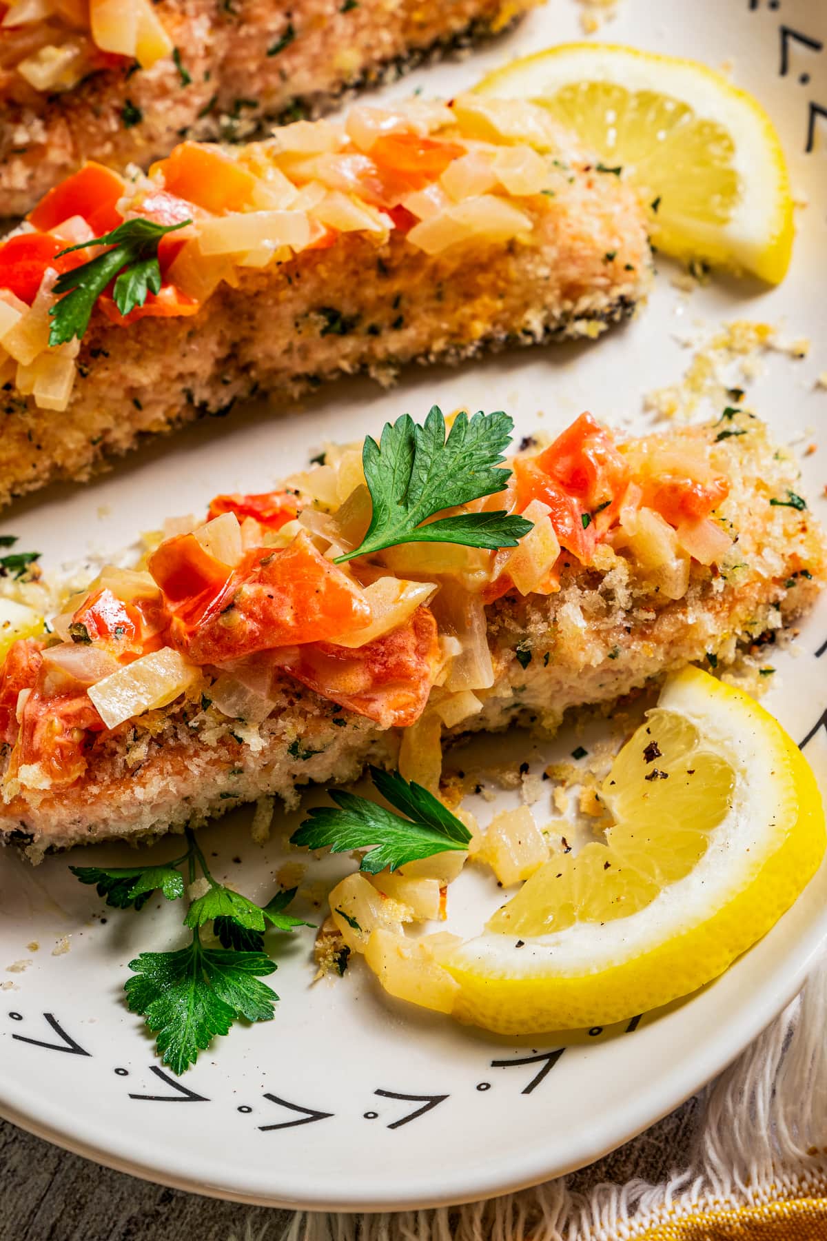 Close-up photo of panko-crusted salmon fillets topped with Tuscan tomato sauce.
