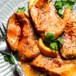 Crockpot orange chicken served on a plate with a fork.