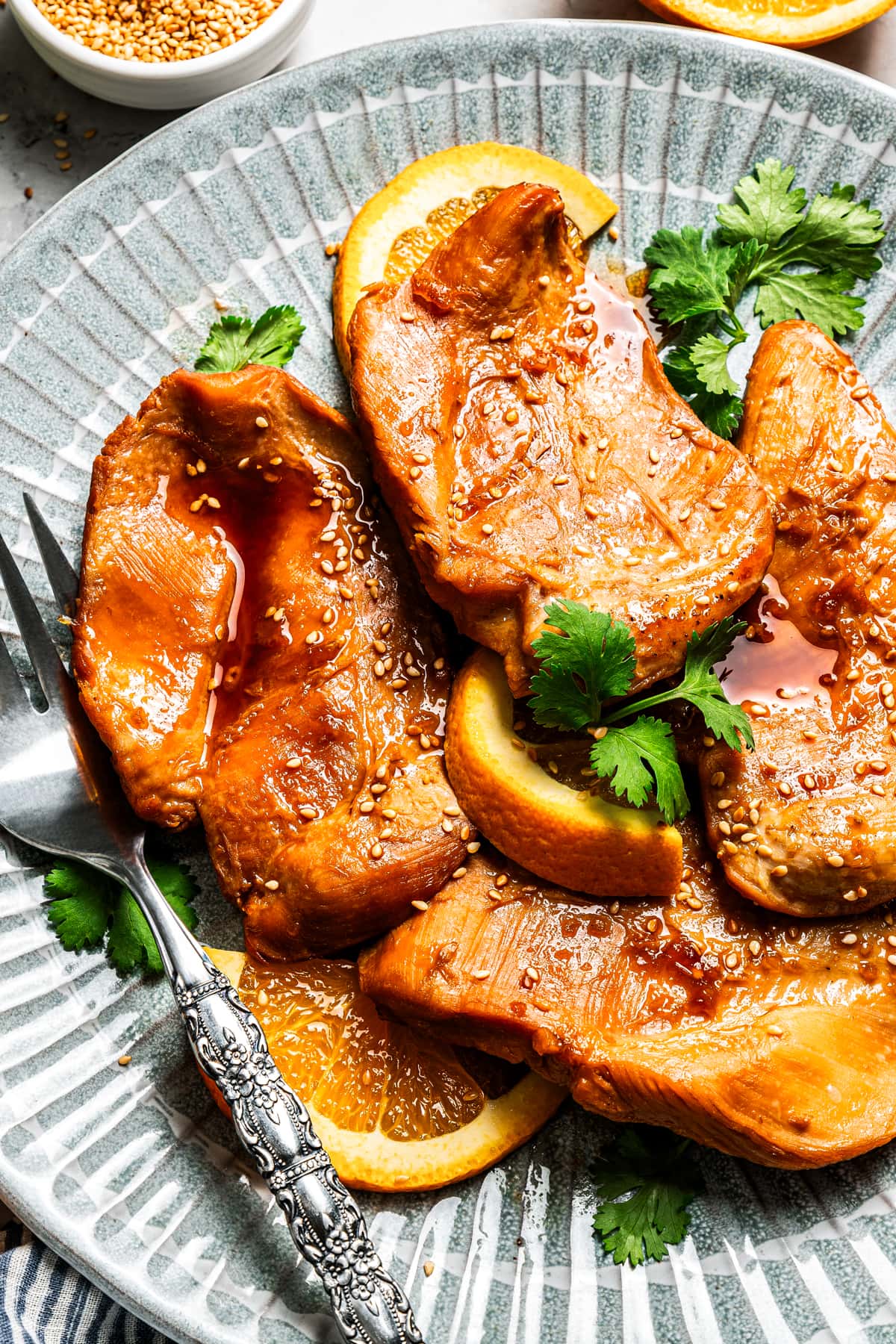 Crockpot orange chicken served on a plate with a fork.