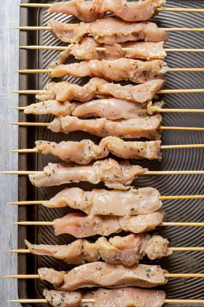 Grilling chicken threaded onto wood skewers