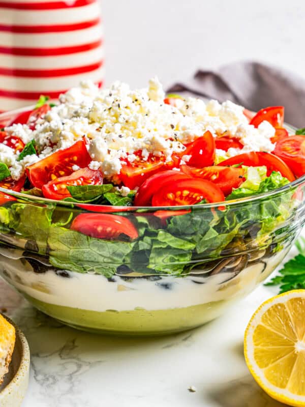 Side view of Mediterranean seven layer dip in a glass bowl, showing the different layers.