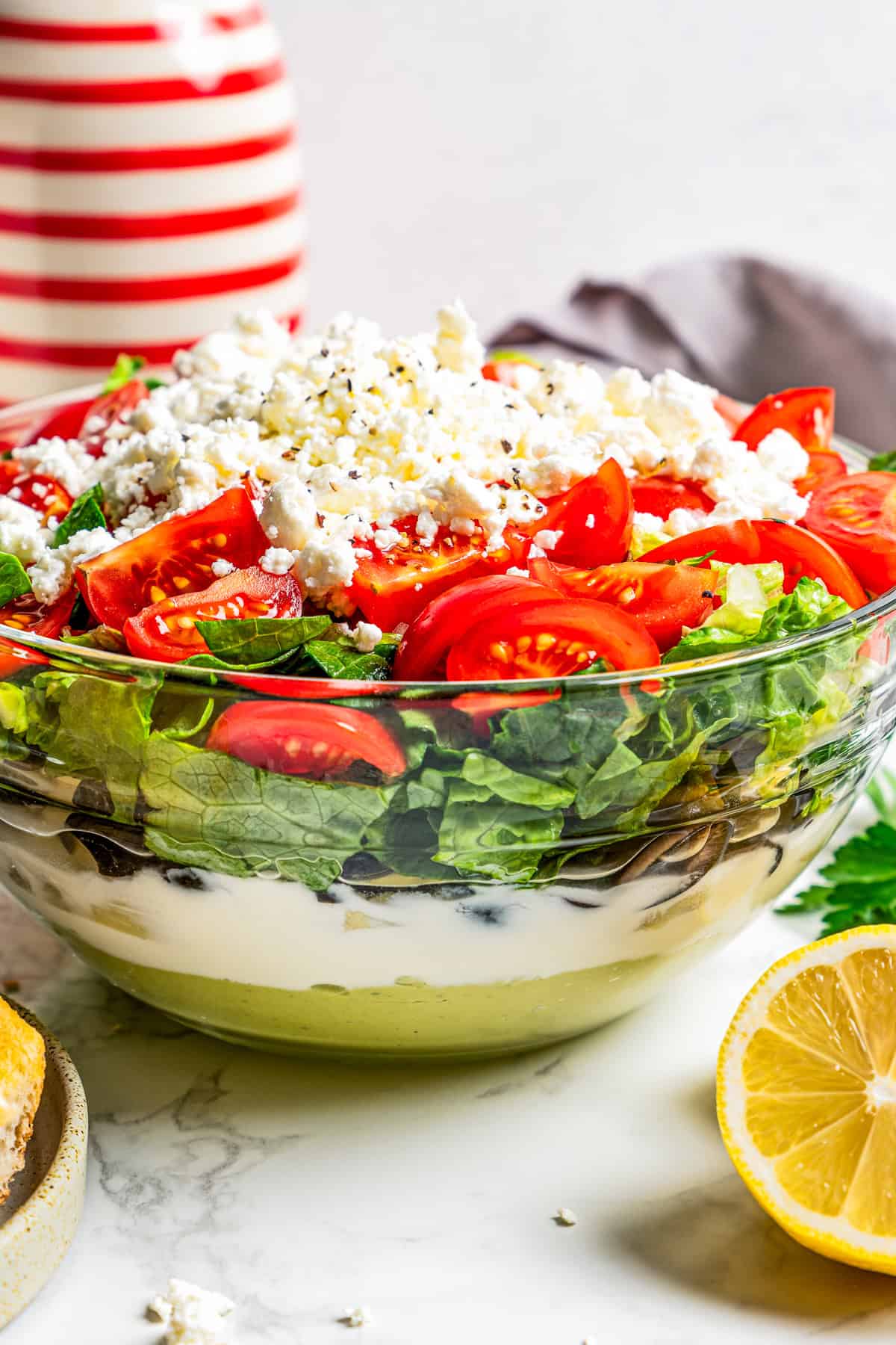 Side view of Mediterranean seven layer dip in a glass bowl, showing the different layers.