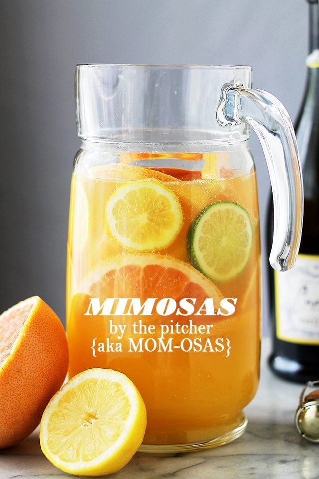 Mimosa and fresh citrus slices served in a glass pitcher