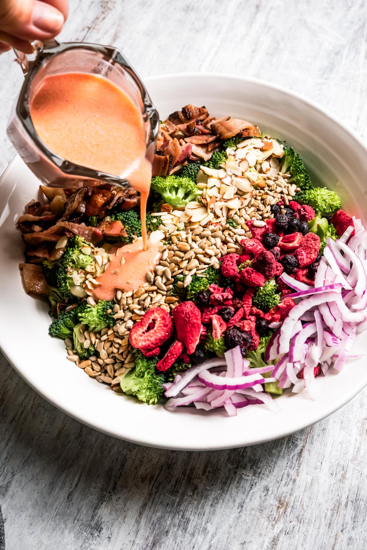 Pouring raspberry vinaigrette over broccoli salad.