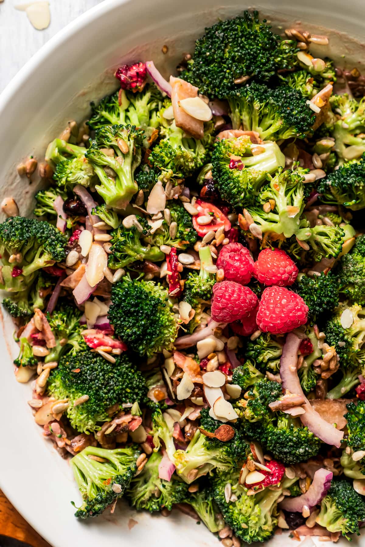 Overhead image of broccoli salad in a serving bowl with a couple of fresh raspberries.