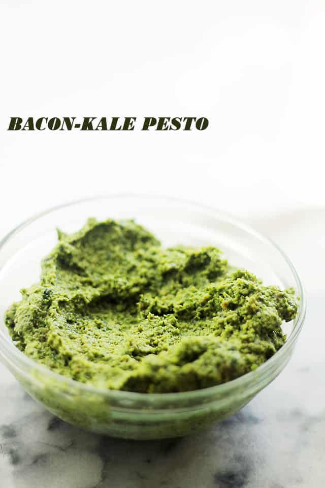A small dish full of fresh and creamy pesto with bacon bits in it.