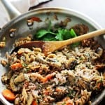 Mushroom orzo pilaf in a metal skillet with a wooden spoon.