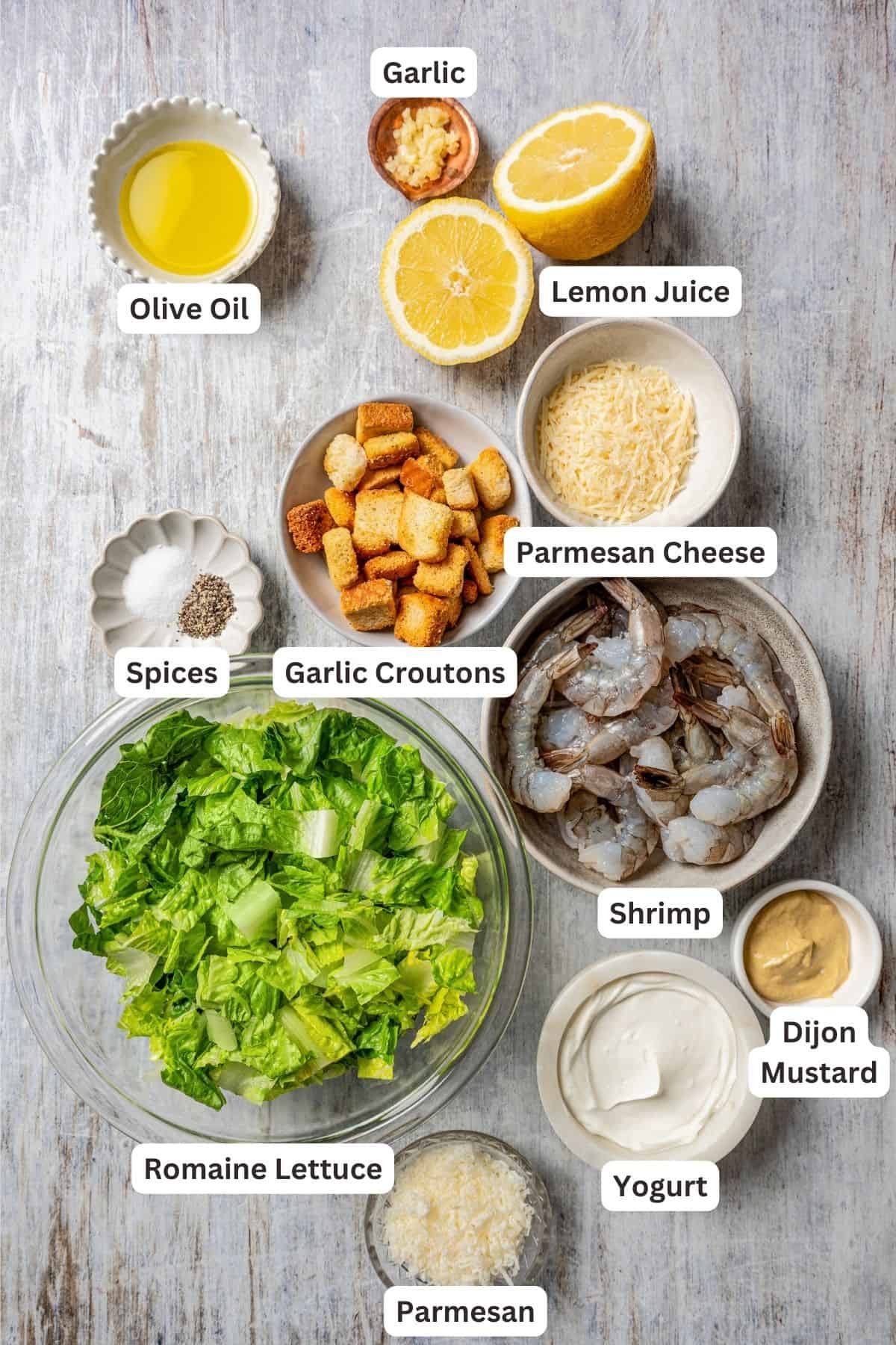 Ingredients for shrimp Caesar salad with text labels overlaying each ingredient.