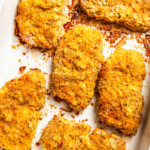 Baked breaded pork chops in a ceramic baking dish.
