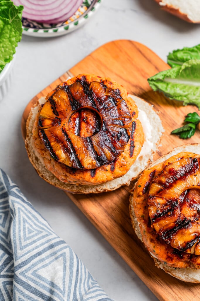 Topping grilled salmon burgers with grilled pineapple rings.