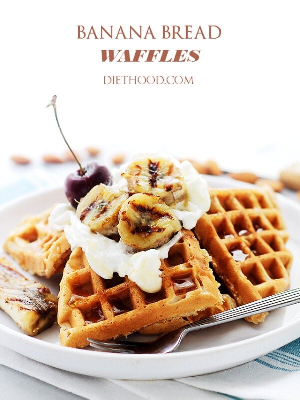 A stack of banana bread waffles topped with whipped cream and grilled banana slices on a white plate.