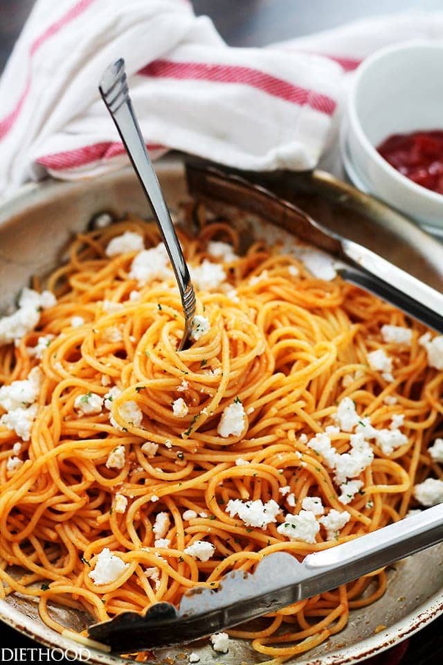 Image of a skillet with ketchup spaghetti and crumbled feta cheese.