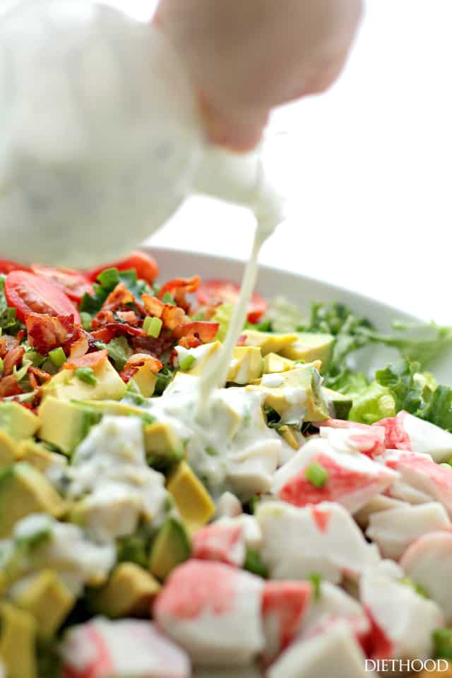 pouring creamy dressing over a Healthy Salad With crab and Avocado. 